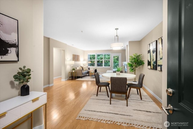 dining area featuring light wood finished floors and baseboards