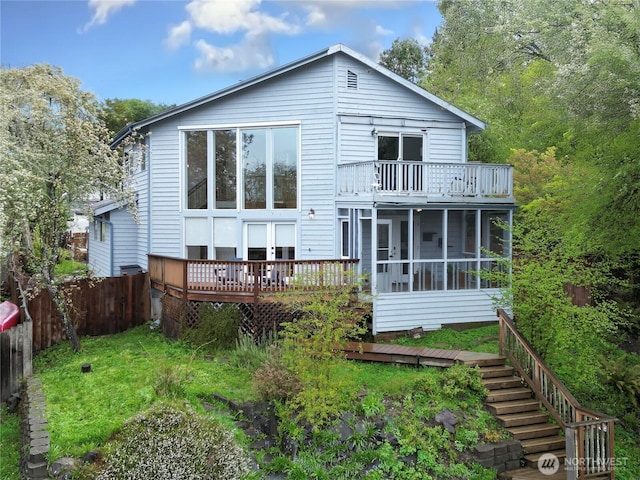 back of house featuring fence, a wooden deck, and a sunroom