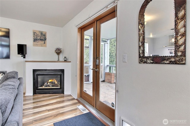 doorway with visible vents, a glass covered fireplace, and wood finished floors
