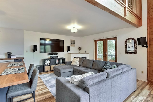 living area with baseboards, french doors, and light wood-style flooring