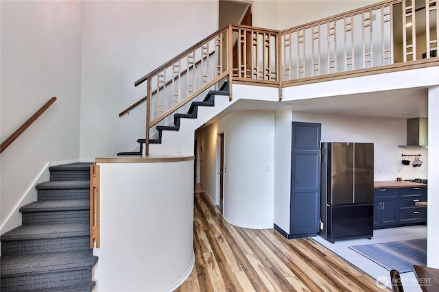 stairway with baseboards, a high ceiling, and wood finished floors
