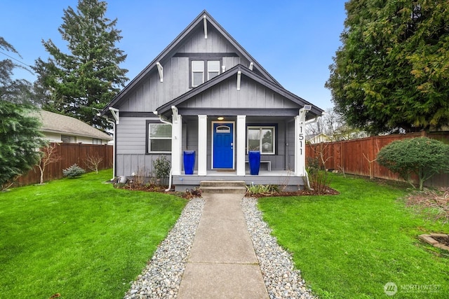 bungalow with board and batten siding, fence private yard, a porch, and a front lawn