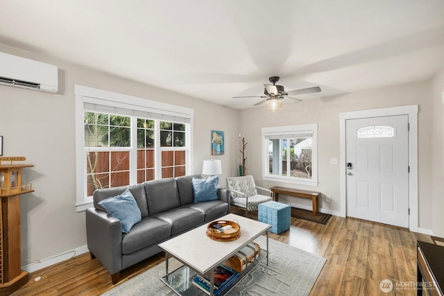 living area featuring a wall unit AC, plenty of natural light, and wood finished floors