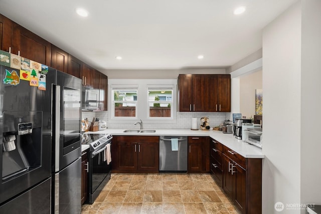 kitchen featuring appliances with stainless steel finishes, light countertops, a sink, and backsplash