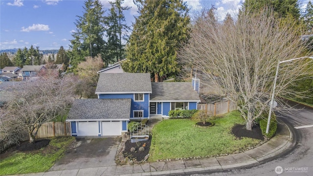 view of front facade featuring a garage, driveway, a front lawn, and fence