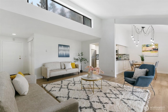 living room featuring light wood finished floors, a high ceiling, and baseboards