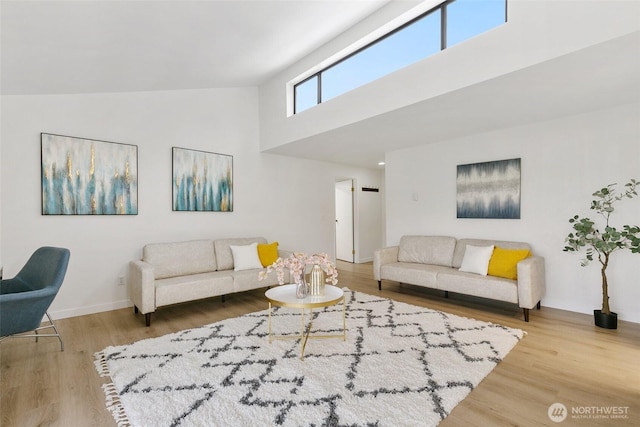 living area featuring wood finished floors, a towering ceiling, and baseboards