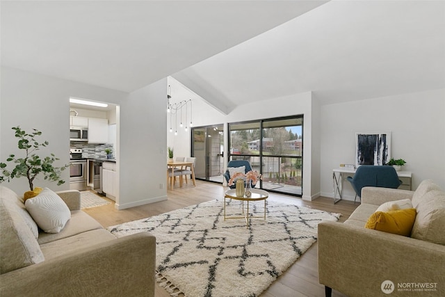 living area with vaulted ceiling, light wood-style flooring, and baseboards