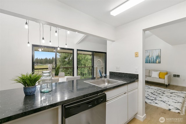 kitchen featuring visible vents, light wood-type flooring, stainless steel dishwasher, white cabinetry, and a sink