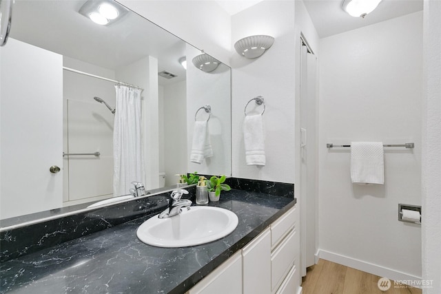 full bath with visible vents, vanity, wood finished floors, a shower with curtain, and baseboards