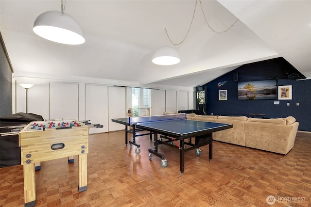 game room with lofted ceiling and a decorative wall