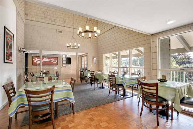 dining space featuring a towering ceiling, an inviting chandelier, and visible vents