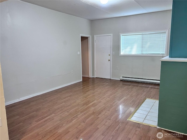 unfurnished room with a baseboard heating unit and hardwood / wood-style floors