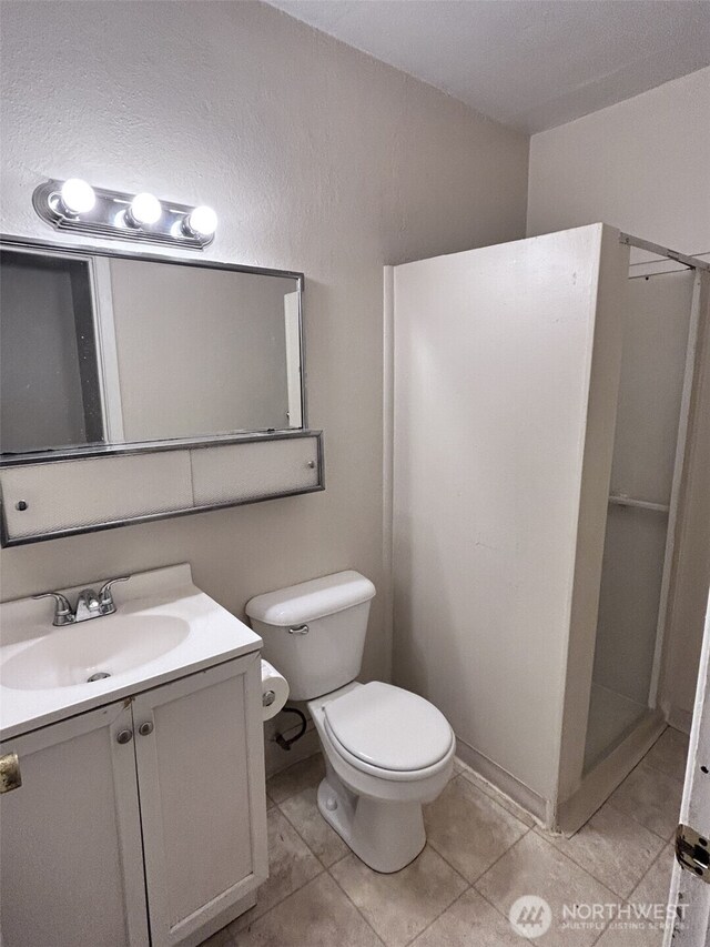 bathroom with walk in shower, vanity, toilet, and tile patterned flooring