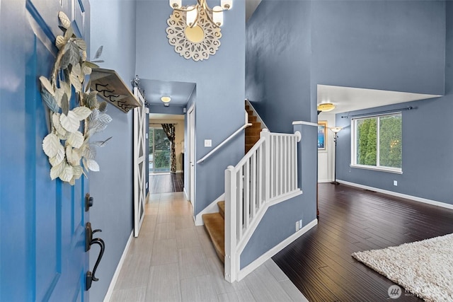 foyer entrance featuring wood-type flooring and a towering ceiling