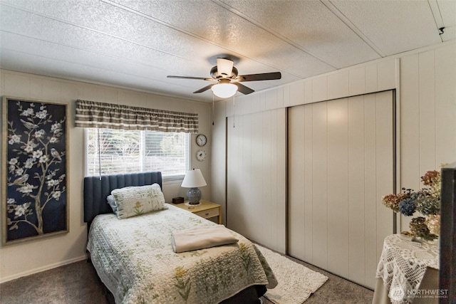 bedroom featuring ceiling fan, a textured ceiling, dark carpet, and a closet