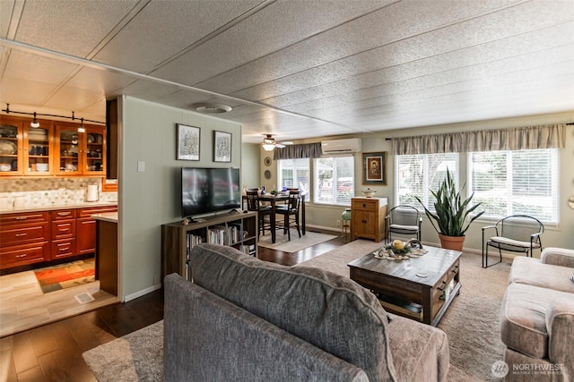 living room with ceiling fan, a wall mounted air conditioner, and hardwood / wood-style floors