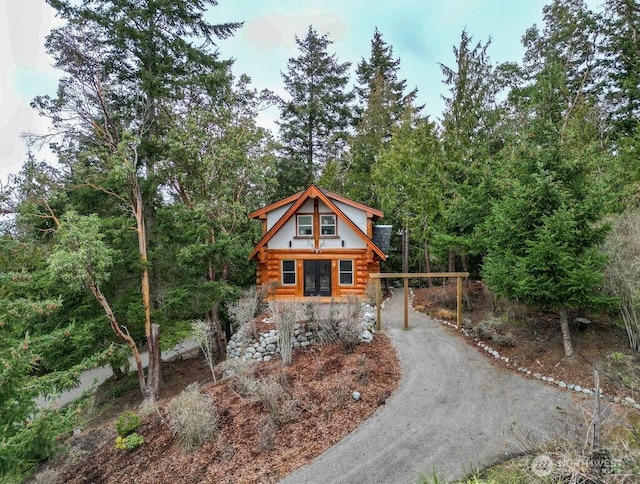 log home with dirt driveway and log siding