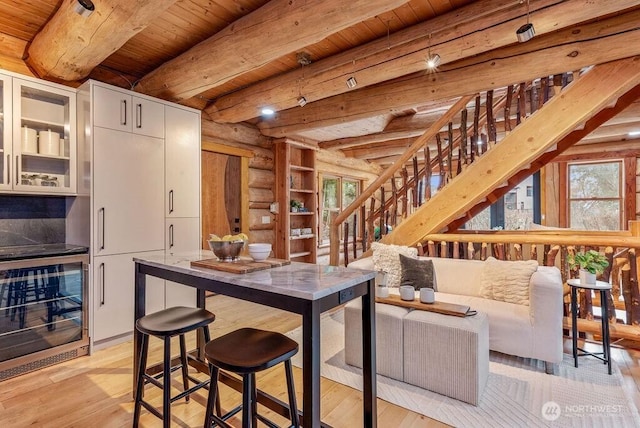 interior space featuring light wood-type flooring, beverage cooler, glass insert cabinets, and a wealth of natural light