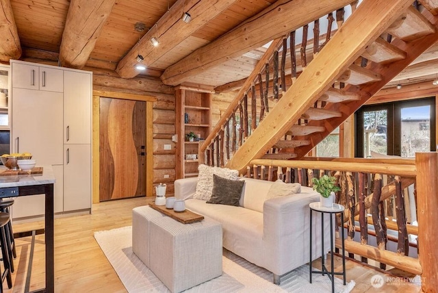 living room with wooden ceiling, light wood-style floors, stairway, log walls, and beam ceiling