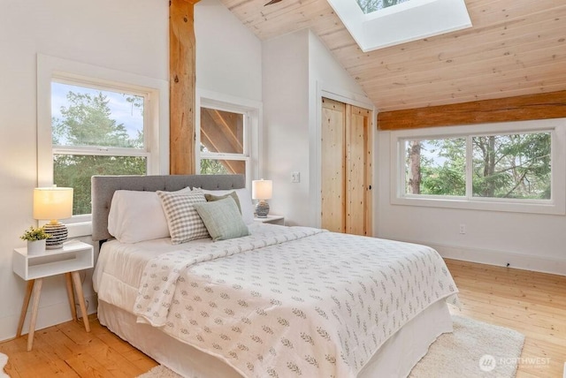 bedroom with vaulted ceiling with skylight, wooden ceiling, baseboards, and light wood finished floors