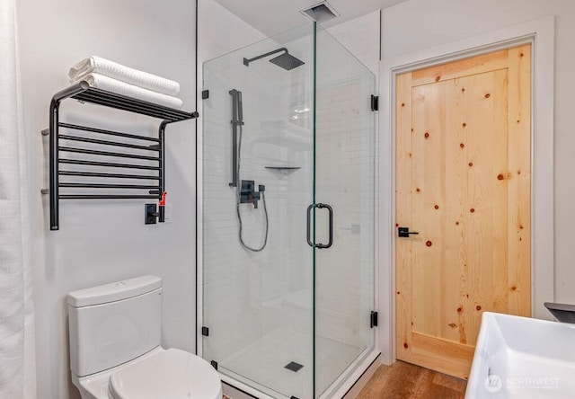 full bath with visible vents, toilet, radiator heating unit, a stall shower, and wood finished floors