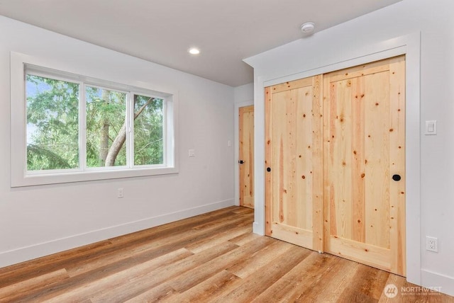 unfurnished bedroom featuring baseboards, wood finished floors, and recessed lighting