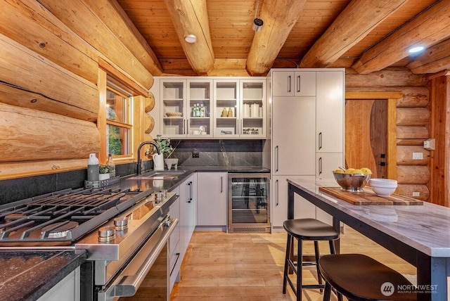 kitchen featuring stainless steel gas stove, wine cooler, glass insert cabinets, white cabinetry, and a sink