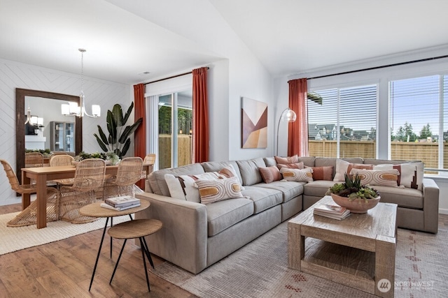 living room with vaulted ceiling, a notable chandelier, and light hardwood / wood-style flooring