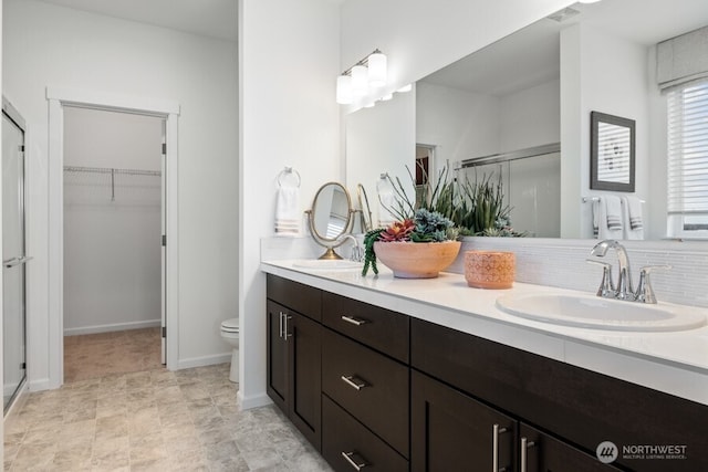 bathroom with walk in shower, vanity, toilet, and backsplash