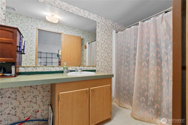 bathroom with vanity, a shower with shower curtain, and a textured ceiling