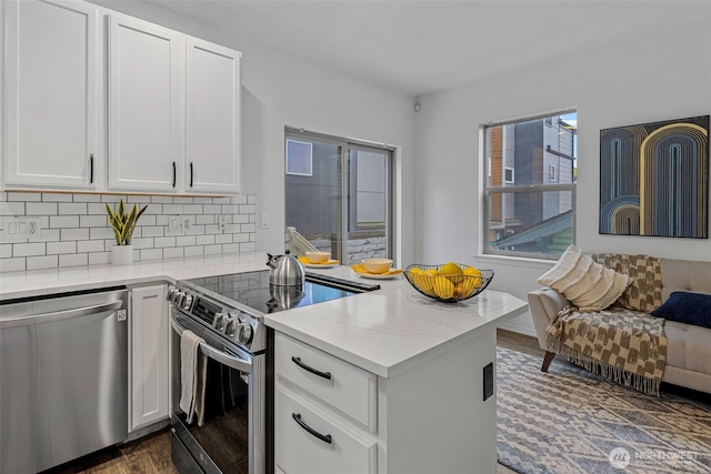 kitchen featuring appliances with stainless steel finishes, tasteful backsplash, light stone countertops, white cabinets, and dark hardwood / wood-style floors