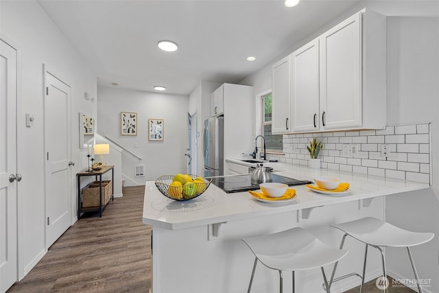 kitchen with white cabinetry, sink, a kitchen breakfast bar, and stainless steel fridge