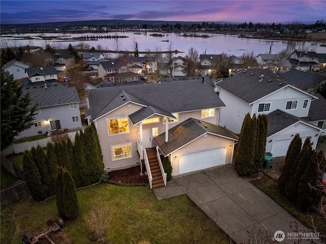 front of property featuring a garage, a water view, and a lawn