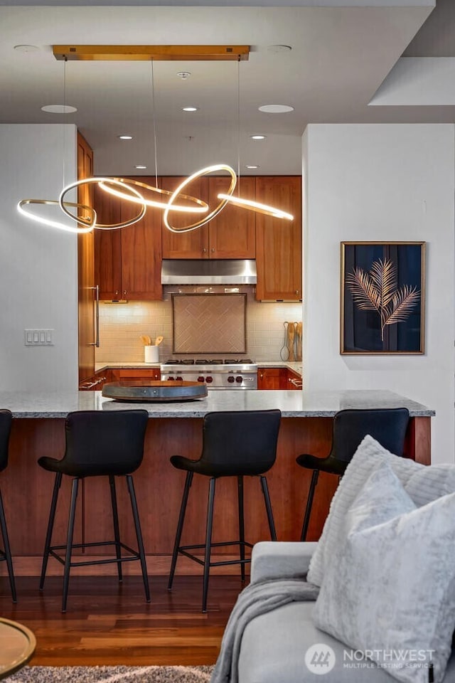 kitchen featuring pendant lighting, a kitchen bar, extractor fan, and stove