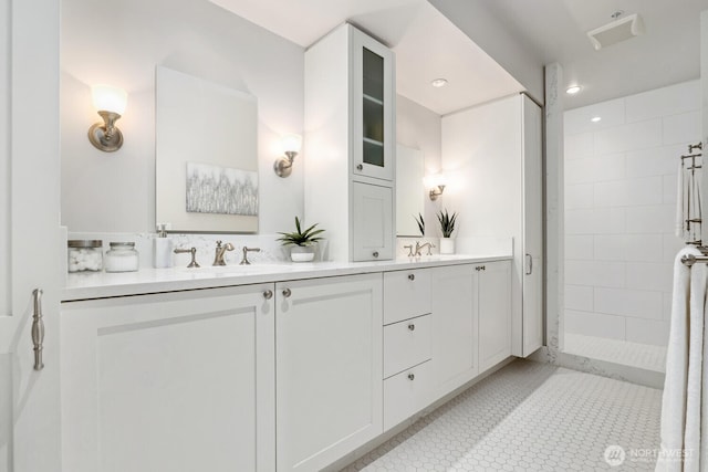 bathroom featuring tile patterned flooring, vanity, and a tile shower