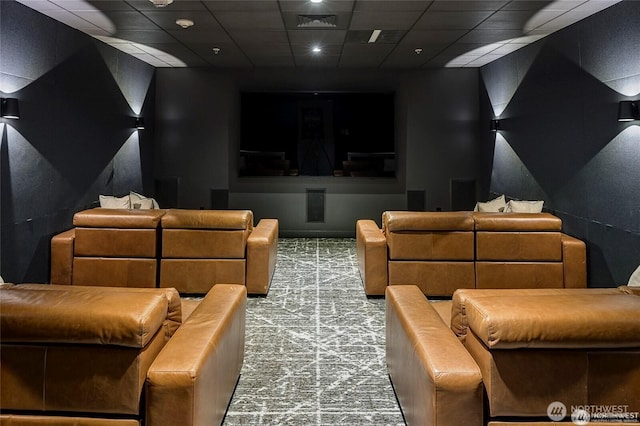 carpeted home theater room with a drop ceiling