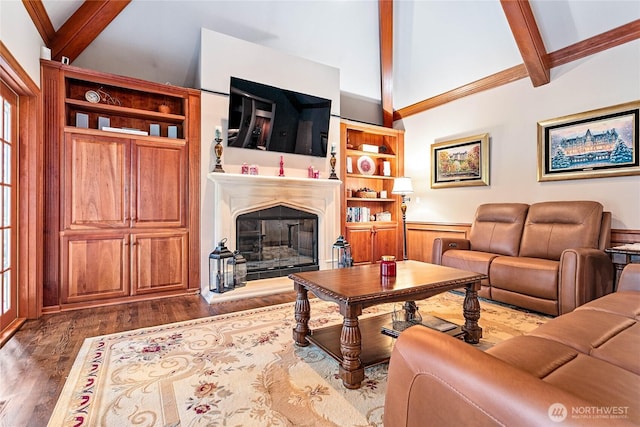 living area with lofted ceiling with beams, a glass covered fireplace, and dark wood-style floors