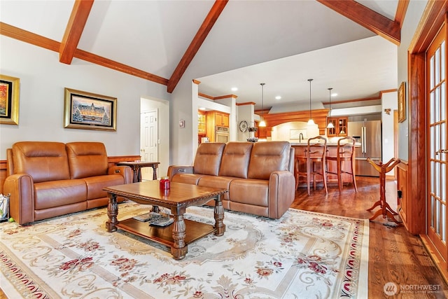 living area with high vaulted ceiling, ornamental molding, wood finished floors, and beam ceiling