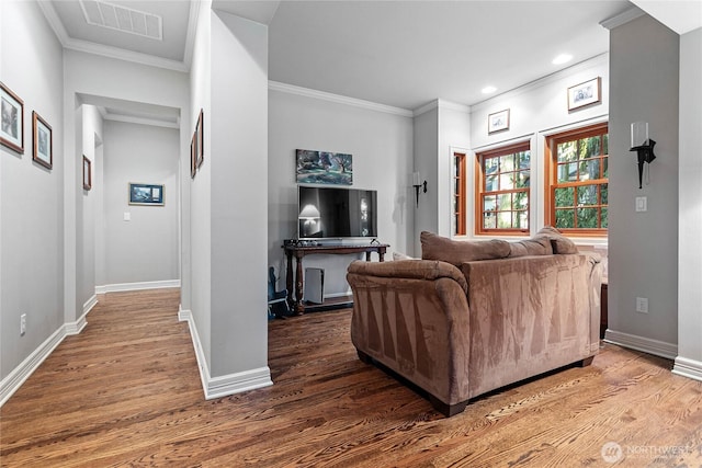 living room with ornamental molding, wood finished floors, visible vents, and baseboards