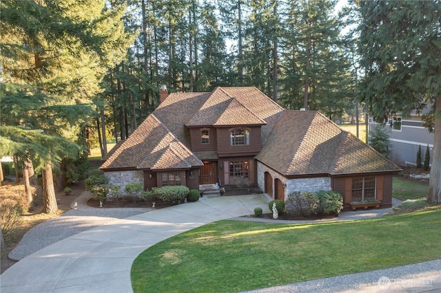 view of front of house featuring a garage, concrete driveway, stone siding, a front lawn, and a chimney