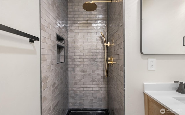 full bathroom featuring tiled shower and vanity