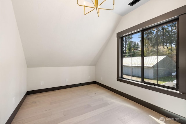 bonus room with light wood-type flooring, an inviting chandelier, baseboards, and lofted ceiling