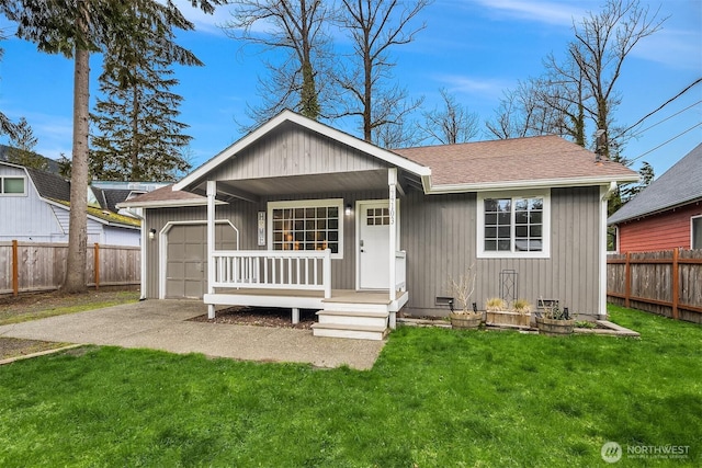 view of front of house featuring a front lawn, fence, a porch, roof with shingles, and driveway