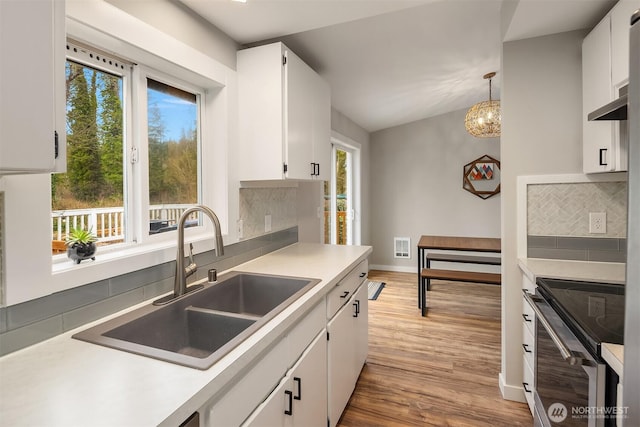 kitchen featuring light wood-style flooring, a sink, backsplash, white cabinetry, and stainless steel electric range