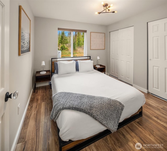 bedroom with dark wood-style floors, a notable chandelier, and baseboards