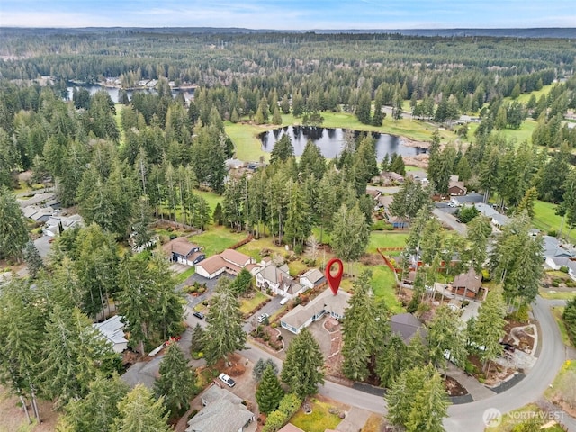 drone / aerial view featuring a wooded view and a water view