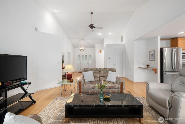 living room with light wood-type flooring, baseboards, high vaulted ceiling, and ceiling fan