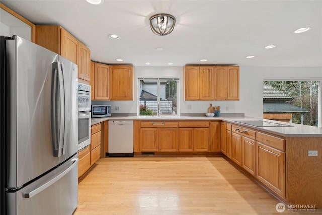 kitchen featuring light wood-type flooring, recessed lighting, stainless steel appliances, a peninsula, and light countertops