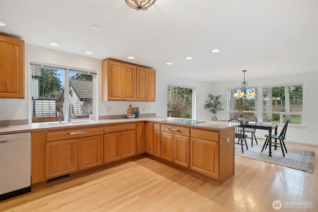 kitchen with dishwasher, light countertops, light wood-style flooring, and a sink